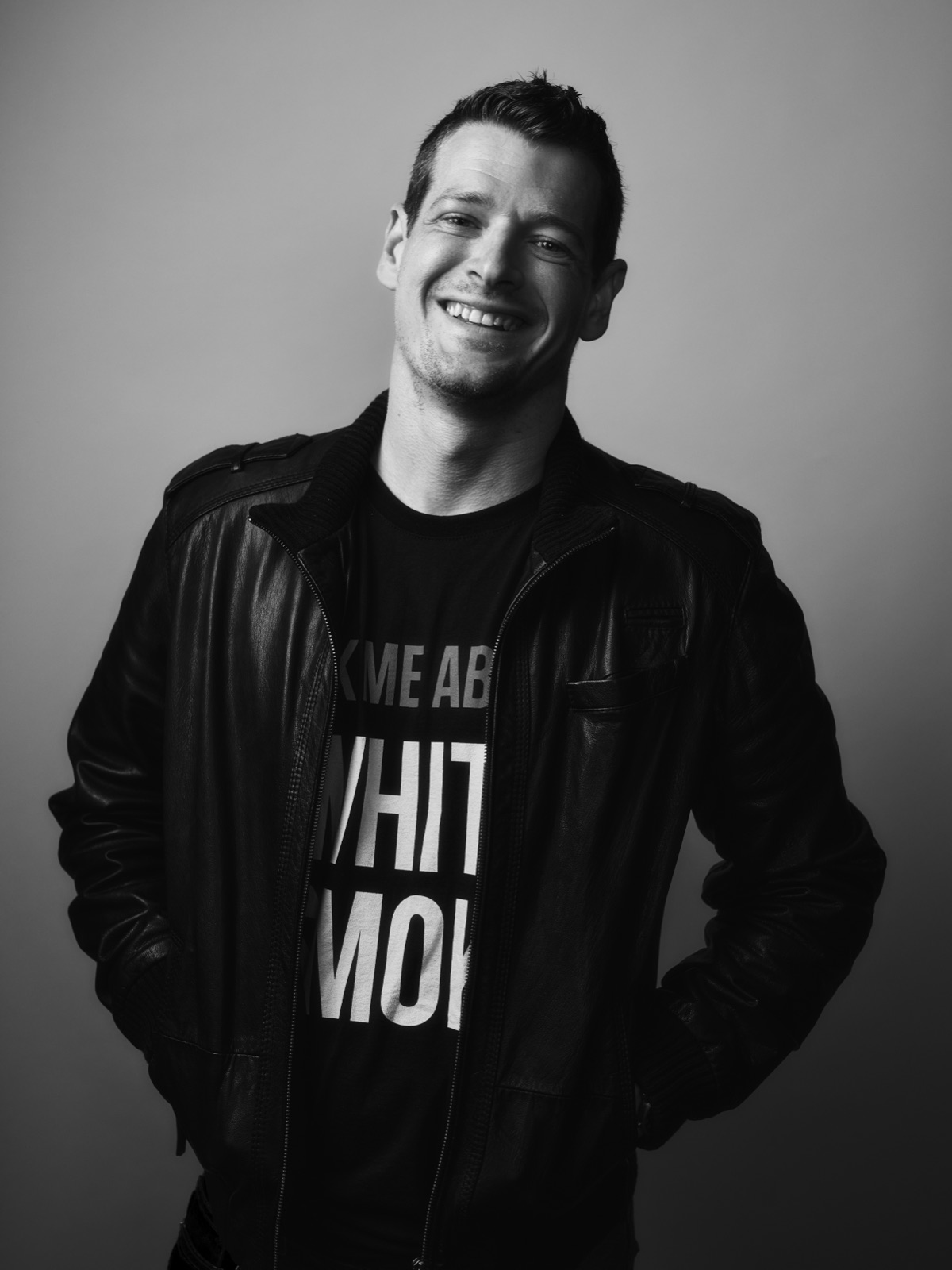 Nick Brucker in a White Smoke t-shirt and leather jacket, black-and-white portrait